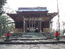 亀岡八幡宮拝殿とその前に置かれた赤いよだれかけを付けた石造狛犬